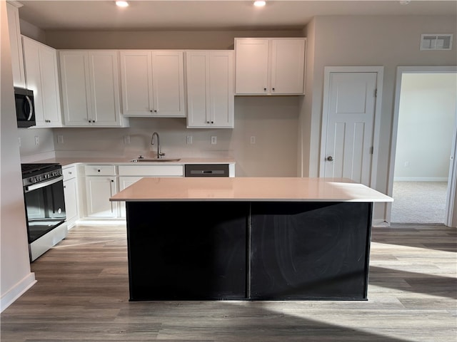 kitchen with a center island, white cabinetry, sink, and stainless steel range