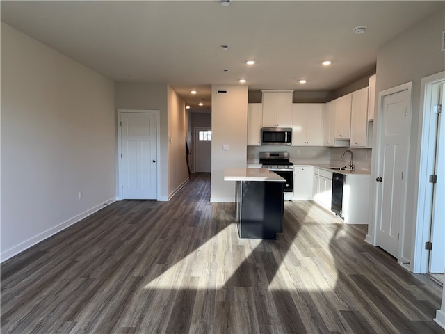 kitchen with sink, white cabinets, dark hardwood / wood-style flooring, a kitchen island, and appliances with stainless steel finishes