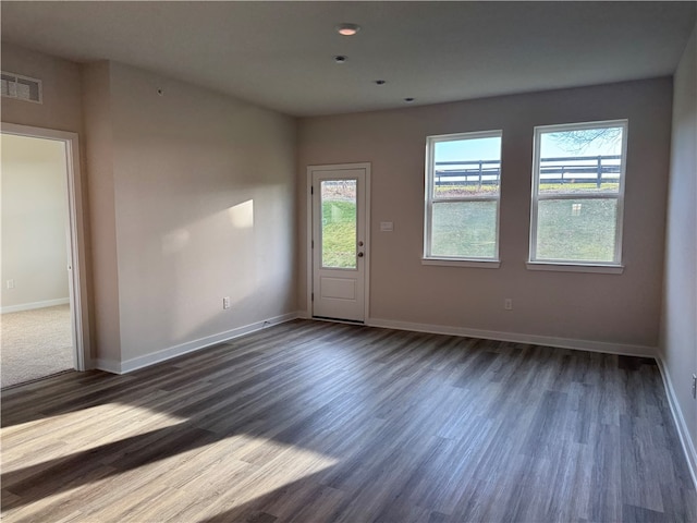 unfurnished room with plenty of natural light and dark wood-type flooring