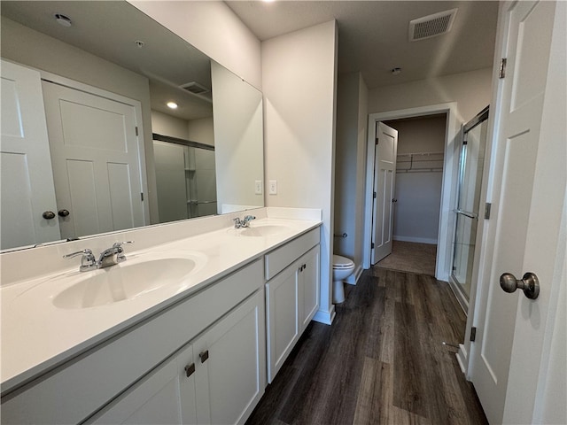 bathroom featuring vanity, hardwood / wood-style flooring, toilet, and a shower with door