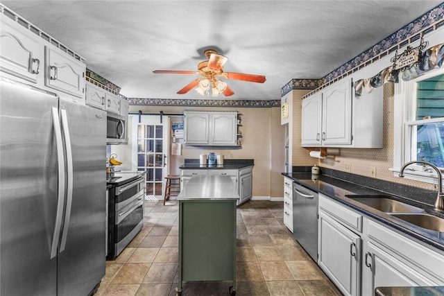 kitchen featuring appliances with stainless steel finishes, ceiling fan, sink, a center island, and white cabinetry