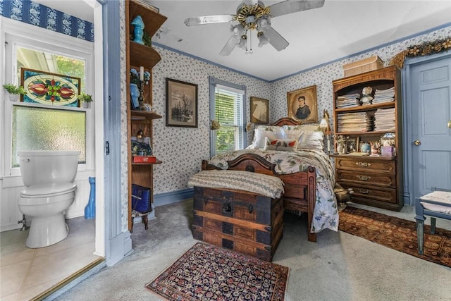 bedroom with ceiling fan, carpet floors, multiple windows, and ensuite bath