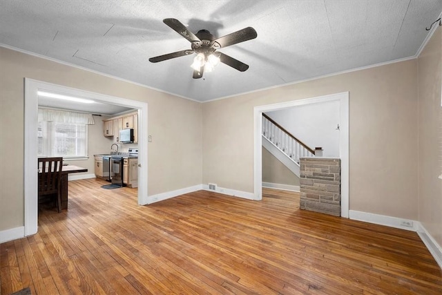 unfurnished living room with a textured ceiling, light hardwood / wood-style flooring, ceiling fan, and ornamental molding