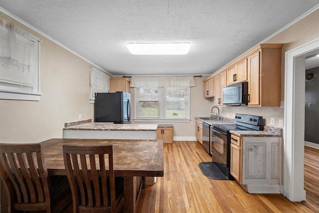 kitchen with light wood-type flooring, a textured ceiling, sink, black appliances, and light brown cabinets