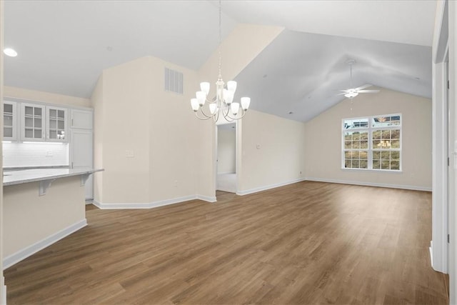 unfurnished living room featuring lofted ceiling, ceiling fan with notable chandelier, and dark hardwood / wood-style floors