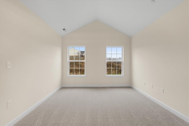 carpeted empty room with vaulted ceiling