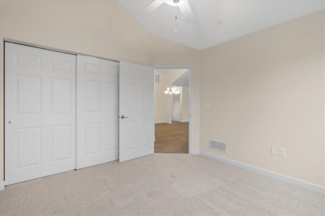 unfurnished bedroom featuring ceiling fan with notable chandelier, light colored carpet, and a closet