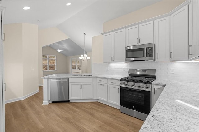 kitchen with white cabinetry, sink, stainless steel appliances, pendant lighting, and lofted ceiling