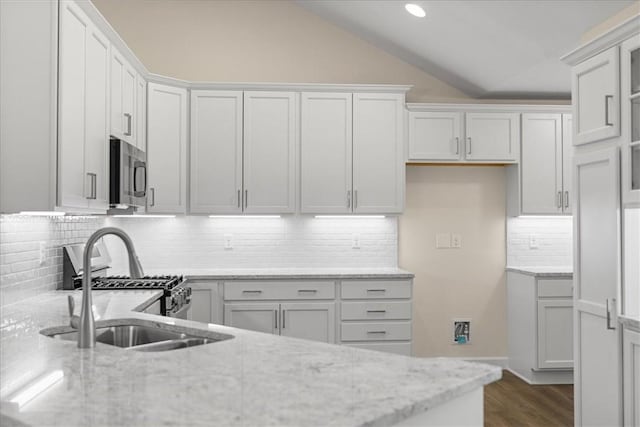 kitchen with light stone countertops, appliances with stainless steel finishes, tasteful backsplash, and white cabinetry