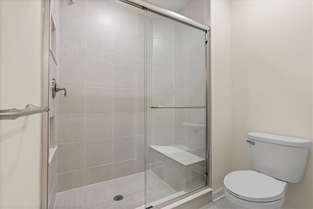 bathroom with a shower with shower door and toilet