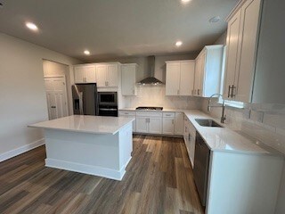 kitchen featuring white cabinets, stainless steel fridge, a center island, and wall chimney range hood