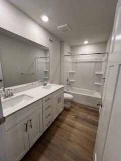 full bathroom featuring vanity, wood-type flooring, bathtub / shower combination, and toilet