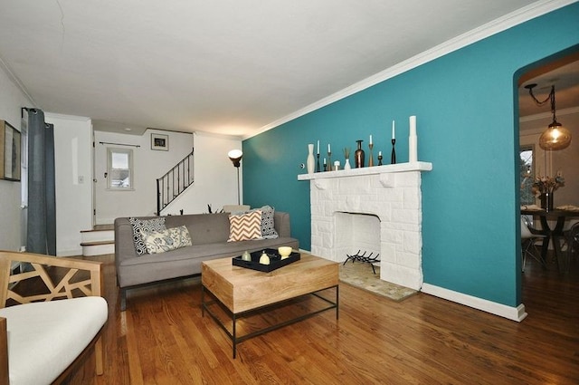 living room featuring hardwood / wood-style floors, a stone fireplace, and ornamental molding