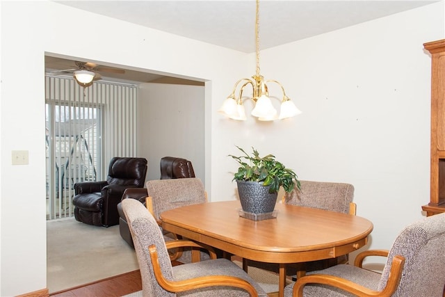 dining room with hardwood / wood-style floors and ceiling fan with notable chandelier