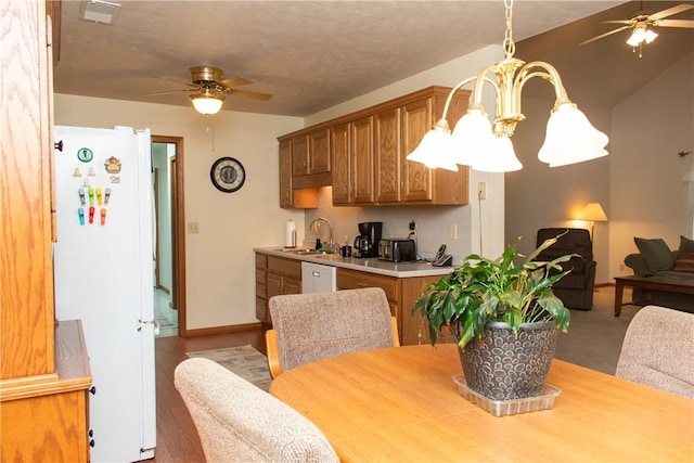 kitchen featuring ceiling fan with notable chandelier, white appliances, hanging light fixtures, and sink