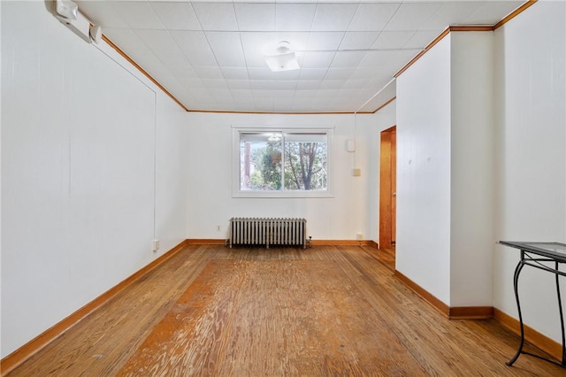 spare room with radiator heating unit, light hardwood / wood-style floors, and ornamental molding