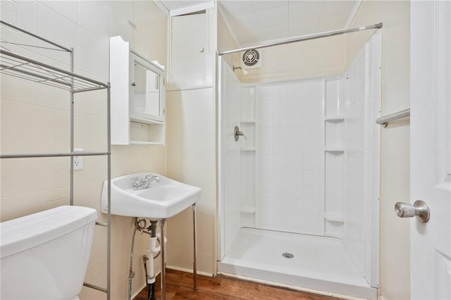 bathroom featuring sink, walk in shower, hardwood / wood-style floors, toilet, and tile walls