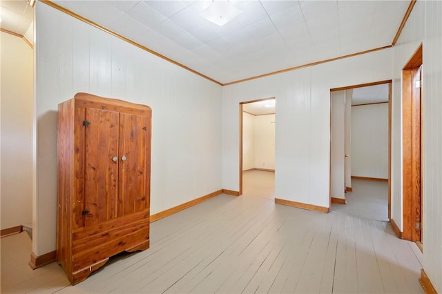 unfurnished bedroom with light wood-type flooring, crown molding, and a closet