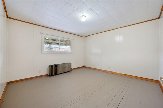 empty room with light hardwood / wood-style flooring, radiator, and crown molding