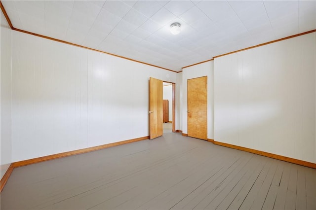 empty room with hardwood / wood-style floors and crown molding