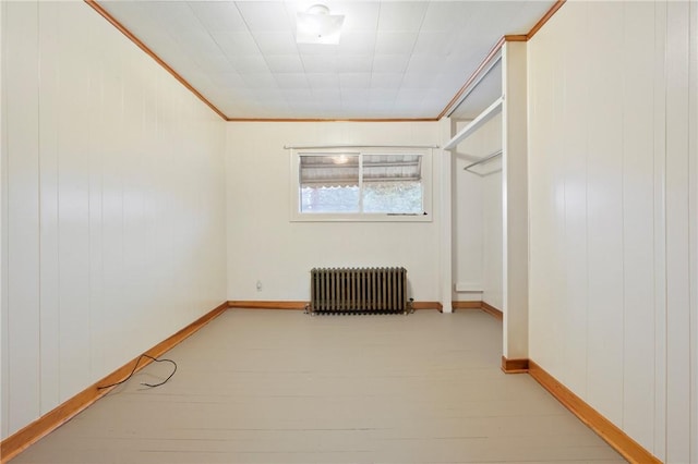 spare room with radiator heating unit, ornamental molding, and light hardwood / wood-style flooring