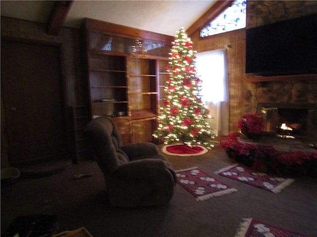 living room featuring vaulted ceiling with beams, wood walls, and a fireplace