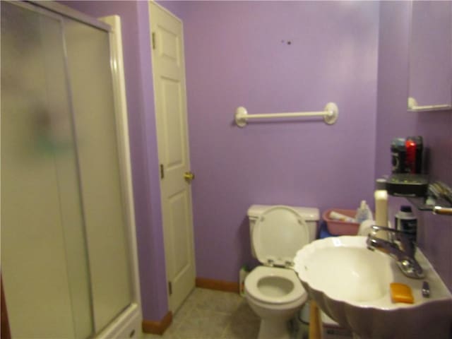 bathroom featuring tile patterned flooring, toilet, walk in shower, and sink