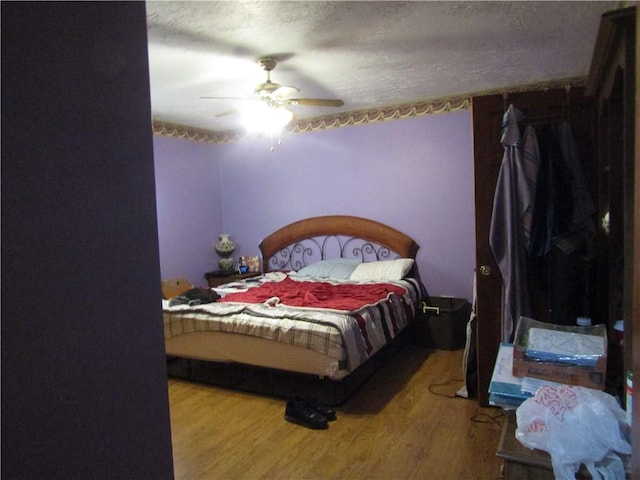 bedroom featuring hardwood / wood-style floors, a textured ceiling, and ceiling fan