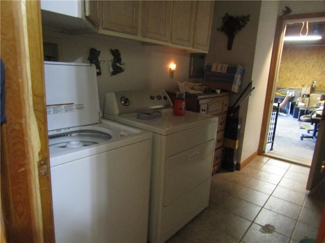 clothes washing area featuring washing machine and clothes dryer, light tile patterned flooring, and cabinets