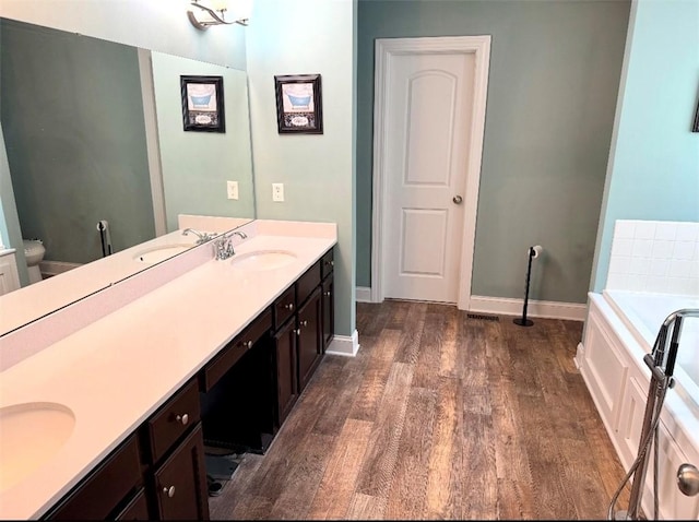 bathroom featuring vanity, hardwood / wood-style flooring, toilet, and a bathtub