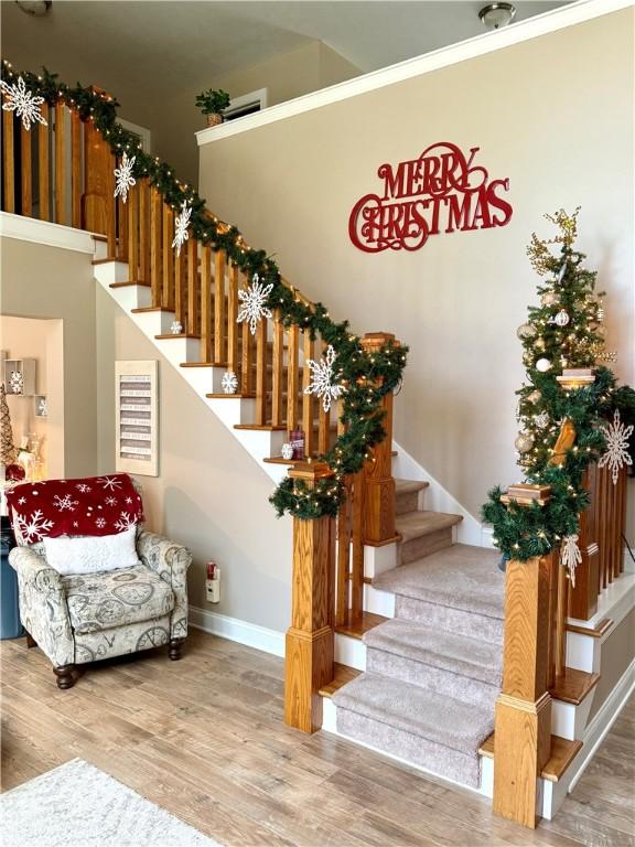 stairway with wood-type flooring and ornamental molding