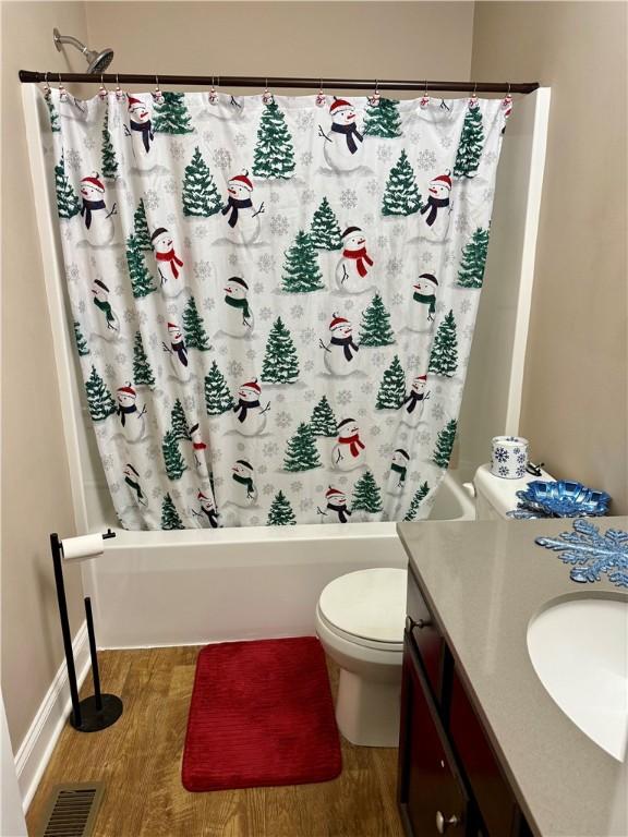 full bathroom with hardwood / wood-style flooring, vanity, toilet, and shower / tub combo with curtain