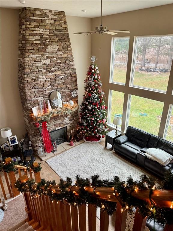 living room featuring hardwood / wood-style flooring, a stone fireplace, and ceiling fan