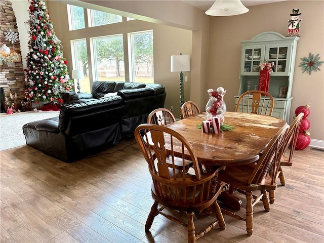 dining area featuring a stone fireplace and light hardwood / wood-style floors