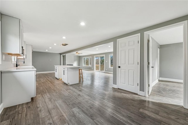 kitchen featuring ceiling fan, white cabinetry, sink, a breakfast bar, and a kitchen island