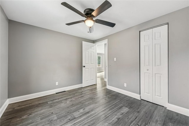 unfurnished bedroom with dark hardwood / wood-style flooring, ceiling fan, and a closet