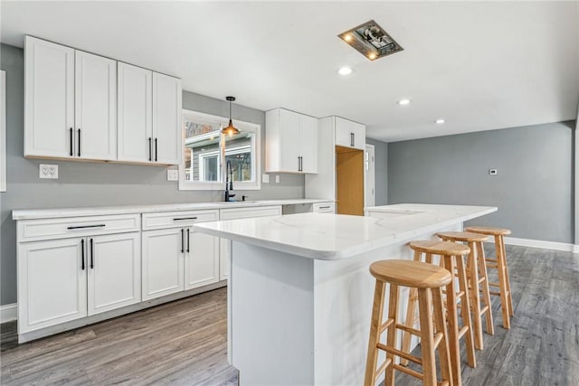 kitchen featuring a center island, white cabinets, wood-type flooring, and decorative light fixtures