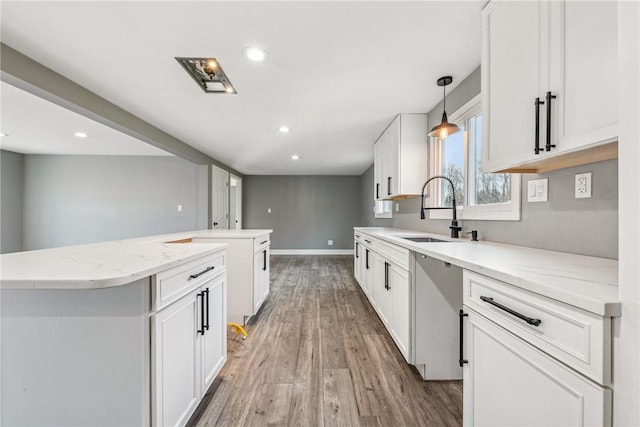 kitchen featuring a center island, sink, hanging light fixtures, light hardwood / wood-style floors, and white cabinetry