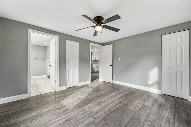 unfurnished bedroom featuring ensuite bathroom, ceiling fan, and dark wood-type flooring