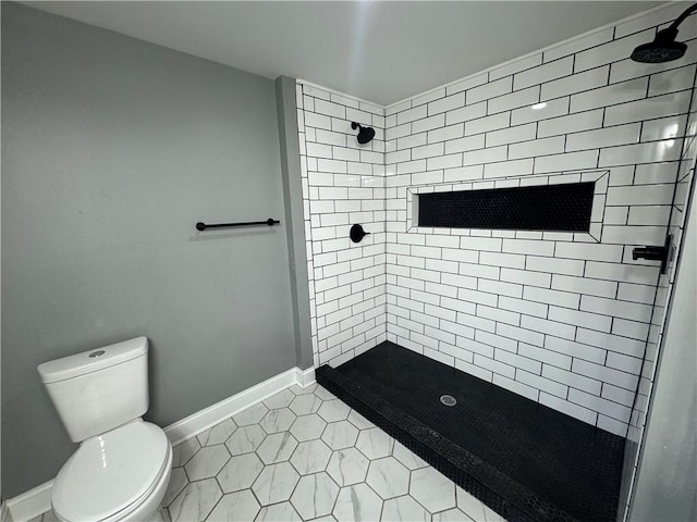 bathroom featuring tile patterned floors, toilet, and tiled shower