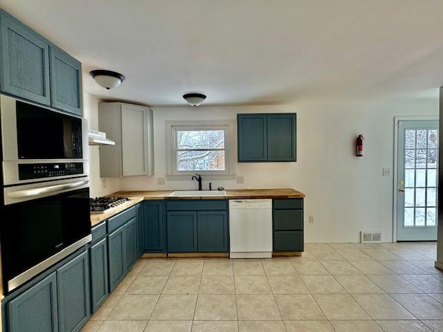 kitchen with sink, light tile patterned floors, and stainless steel appliances