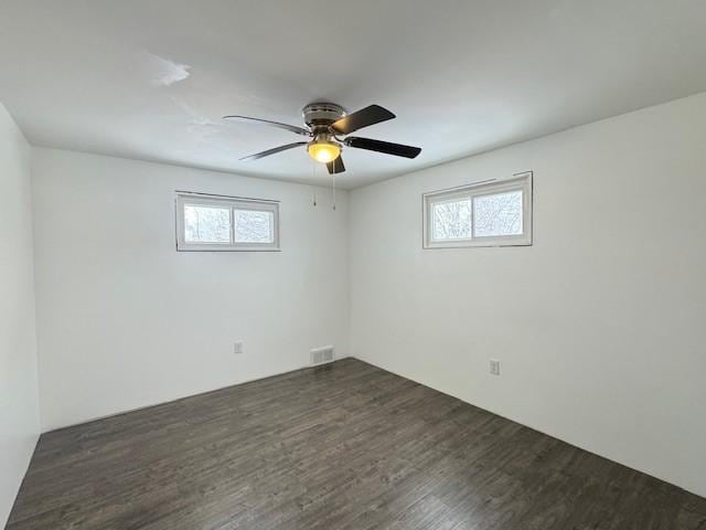 unfurnished room featuring ceiling fan, a healthy amount of sunlight, and dark hardwood / wood-style flooring