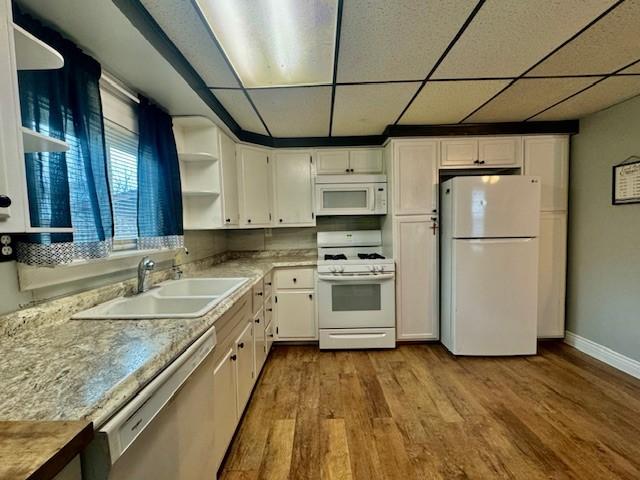 kitchen with sink, light hardwood / wood-style flooring, white appliances, a paneled ceiling, and white cabinets