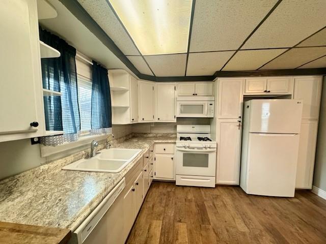 kitchen with white cabinets, dark hardwood / wood-style floors, a paneled ceiling, and white appliances