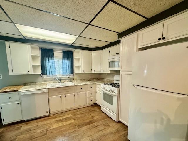 kitchen with white appliances, light hardwood / wood-style flooring, white cabinetry, and a paneled ceiling