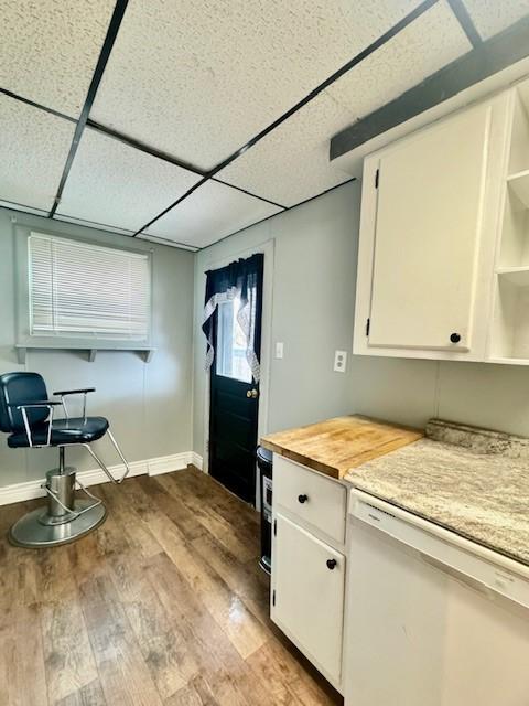 kitchen with white cabinets, dishwasher, a paneled ceiling, and light hardwood / wood-style flooring