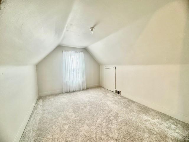 additional living space with light colored carpet and lofted ceiling