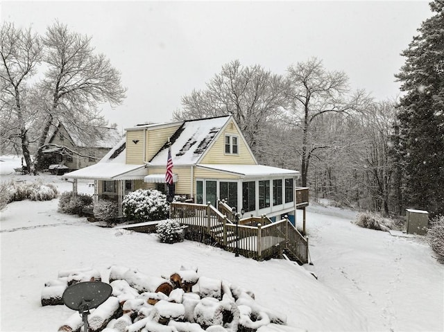 snow covered property featuring a sunroom and a deck