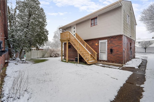 snow covered rear of property with a deck