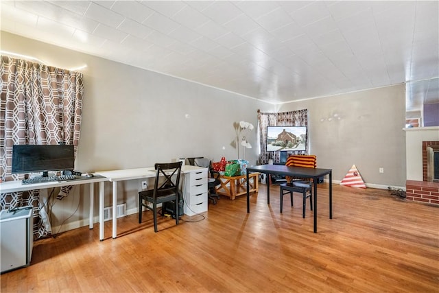 office space featuring light wood-type flooring and a brick fireplace